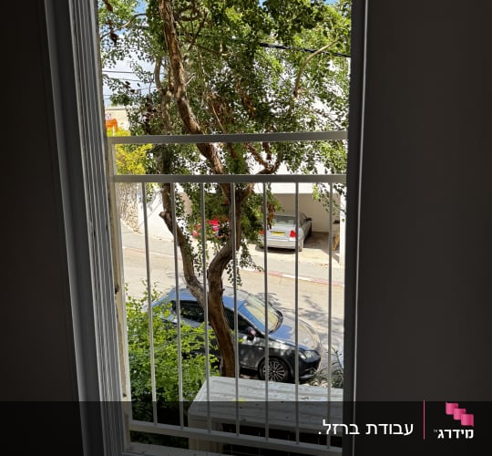 סורג ישר ממתכת בצבע לבן המותקן בחלון דירה